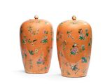 une paire de vases orange ornés d'oiseaux et de fleurs sur un fond blanc