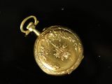 an image of a gold pocket watch on a black surface