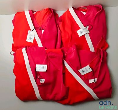 three red shirts with white stripes hang on a wall
