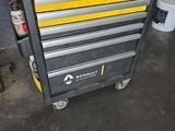 La boîte à outils est posée par terre dans le garage.