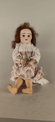 an old fashioned doll sitting on a table with a white background