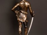 bronze statue of a man with a sword and shield on a marble base
