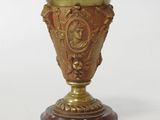 a gold vase sitting on top of a marble base