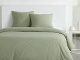 un gros plan sur un lit avec une couette et des oreillers verts