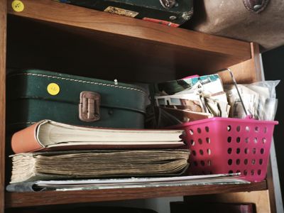 a stack of books on a shelf next to a basket of luggage