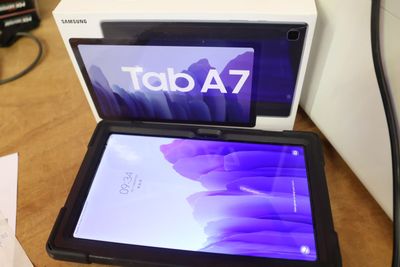 une tablette posée sur une table, à côté d'une boîte