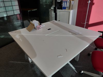 une table blanche sur laquelle est posé un ordinateur portable, dans une pièce