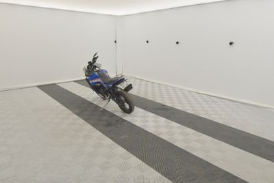une moto qui est garée dans une pièce dont le sol est en damier