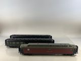 trois trains miniatures sont alignés sur une surface blanche