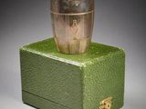 une boîte verte surmontée d'une coupe argentée, posée sur une surface grise