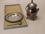 a silver tea pot and a silver plate in a box