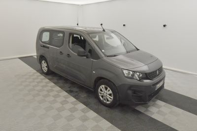 La camionnette grise est garée dans le garage, sur le sol à damier.