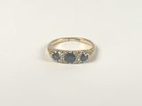 un gros plan d'une bague en or sertie de trois saphirs