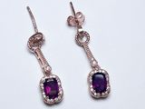 une paire de boucles d'oreilles ornées de pierres violettes sur fond blanc