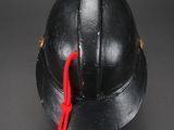 an old helmet with a red string tied to it on a black surface