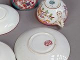 six porcelain teapots and two saucers are sitting on a table