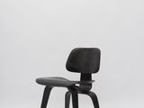 une chaise Eames noire avec une assise en cuir noir sur fond blanc