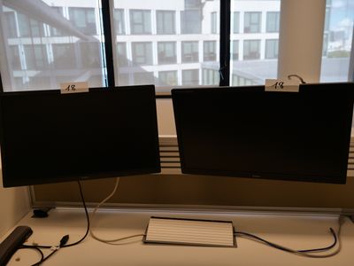 deux écrans posés sur un bureau, avec un clavier et une souris