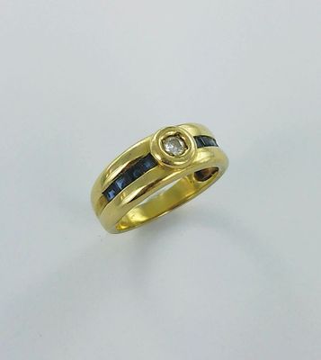 un gros plan d'une bague en or sertie d'un diamant et d'un saphir bleu