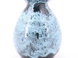 un vase bleu posé sur une surface blanche