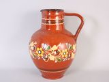 a red vase with a floral design on it
