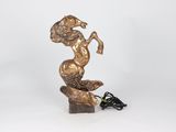 a bronze statue of a woman on a rock with a power cord