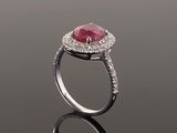an oval ruby and diamond ring on a reflective surface