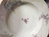 une personne tenant une assiette blanche ornée de fleurs violettes