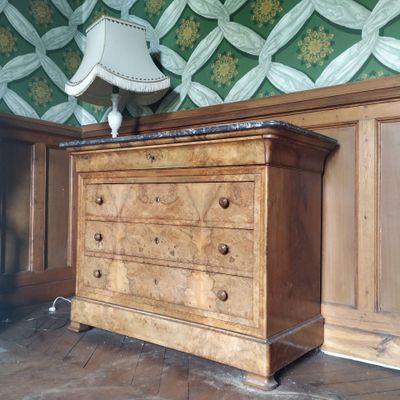 une commode sur laquelle est posée une lampe, dans une pièce