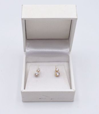 une paire de boucles d'oreilles dans un écrin posé sur une surface blanche