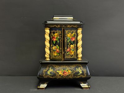 une horloge noire et dorée sur laquelle sont peintes des fleurs
