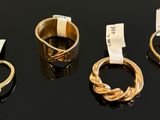 three gold rings and two emerald rings on a black surface