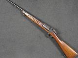 a rifle with a wooden barrel and a wooden handle on a gray surface