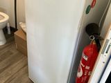 un réfrigérateur blanc et des toilettes dans une petite pièce