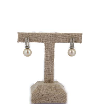 boucles d'oreilles en perles et diamants présentées sur un présentoir, sur fond blanc