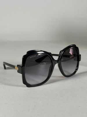 une paire de lunettes de soleil noires posée sur une surface blanche