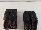 two pairs of black shoes sitting on top of a white surface