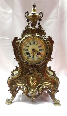 une horloge en or posée sur une table blanche