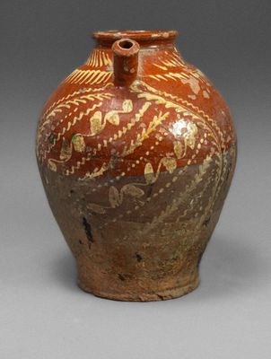a brown vase with gold designs on it on a gray surface