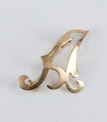 a close up of a gold brooch with a letter a on it