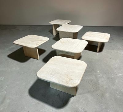 four tables and four stools in a room with a wall in the background