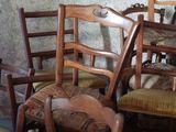 many wooden chairs in a room with a cat sitting on one of them