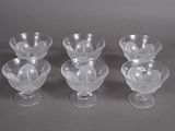 four clear glass bowls with a flower design on them on a gray surface