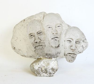 a sculpture of three faces on a rock with a white background