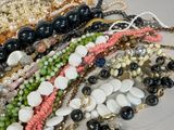many different types of bracelets and necklaces laid out on a table