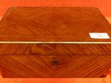 une vieille boîte en bois portant une étiquette, posée sur un tissu orange