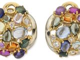 une paire de boucles d'oreilles composées de pierres multicolores et d'or, sur fond blanc