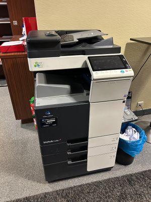 a printer that is sitting on the floor next to a trash can
