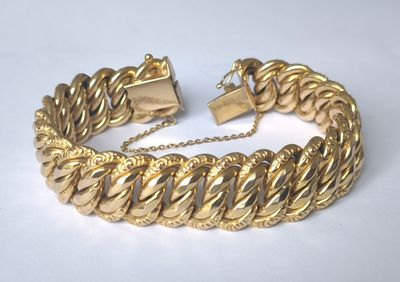 gros plan d'un bracelet en or sur une surface blanche