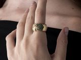 someone is wearing a ring with a green stone on it